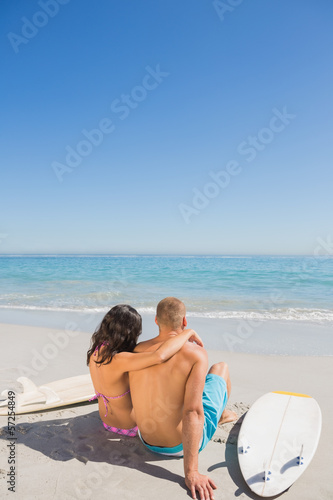 Photo: Cute young couple sitting with their surfboards Cute young couple sitting with their surfboards