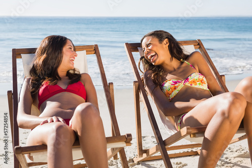 Photo: Cheerful beautiful friends relaxing on their deck chairs Cheerful beautiful friends relaxing on their deck chairs