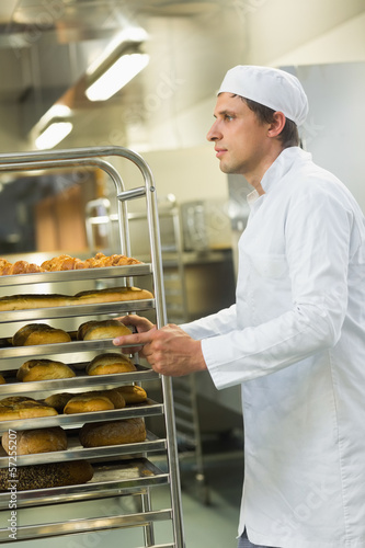 Photo: Handsome young baker pushing a trolley Handsome young baker pushing a trolley