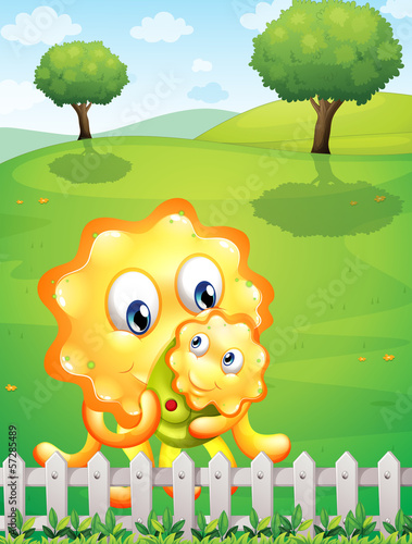 Vector: An orange monster carrying her baby monster at the hilltop An orange monster carrying her baby monster at the hilltop