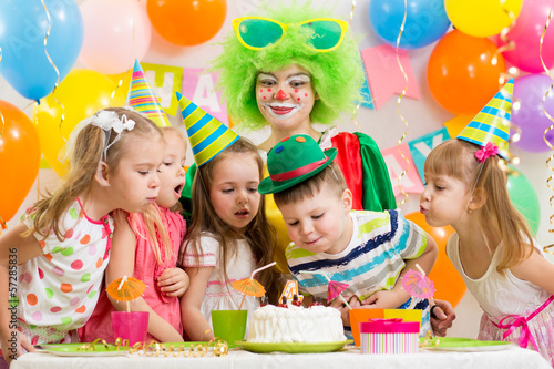 Photo: kids with clown celebrating birthday party and blowing candles o kids with clown celebrating birthday party and blowing candles o