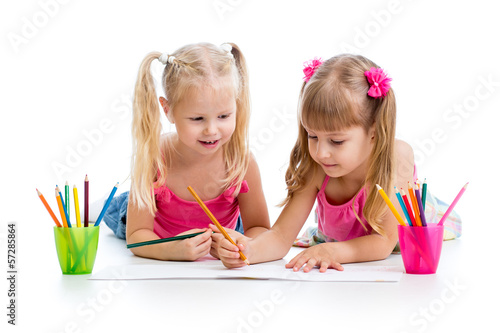 Photo: two girls drawing with color pencils together over white backgro two girls drawing with color pencils together over white backgro