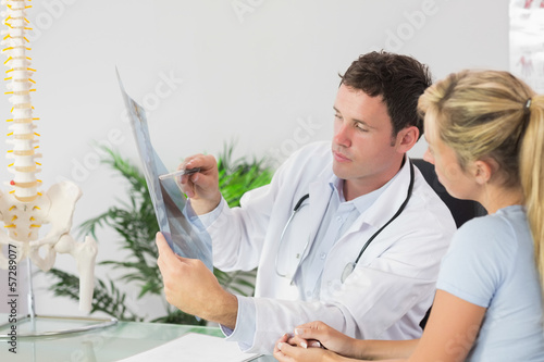 Photo: Handsome doctor showing a patient something on x-ray Handsome doctor showing a patient something on x-ray