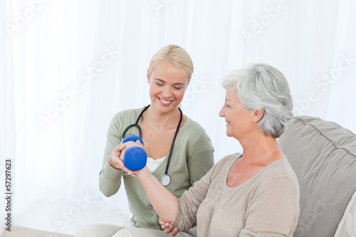 Photo: Beautiful nurse helping her patient to do exercises Beautiful nurse helping her patient to do exercises