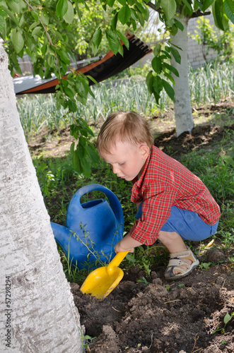 Photo: Cute little boy digging in the garden Cute little boy digging in the garden