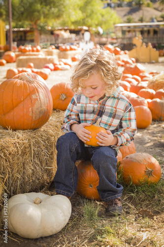 Photo: Little Boy Sitting and Holding His Pumpkin at Pumpkin Patch. Little Boy Sitting and Holding His Pumpkin at Pumpkin Patch.
