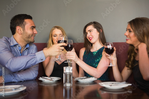 Photo: Friends clinking red wine glasses at a bar Friends clinking red wine glasses at a bar