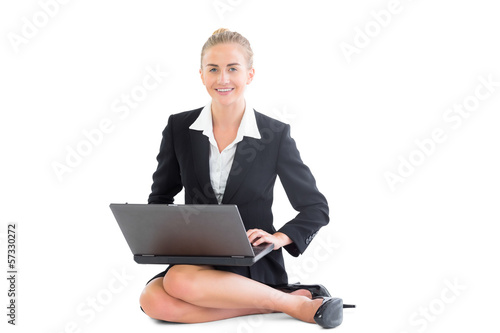 Photo: Cheerful blonde businesswoman sitting on floor working with her Cheerful blonde businesswoman sitting on floor working with her