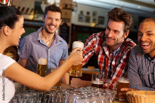 Photo: Friends drinking beer at counter in pub Friends drinking beer at counter in pub