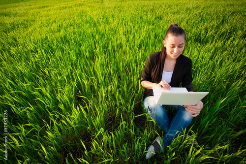 Photo: woman in a green field with a laptop. summer woman in a green field with a laptop. summer