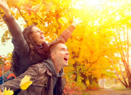 Photo: Happy Couple in Autumn Park. Fall. Family Having Fun Outdoors Happy Couple in Autumn Park. Fall. Family Having Fun Outdoors