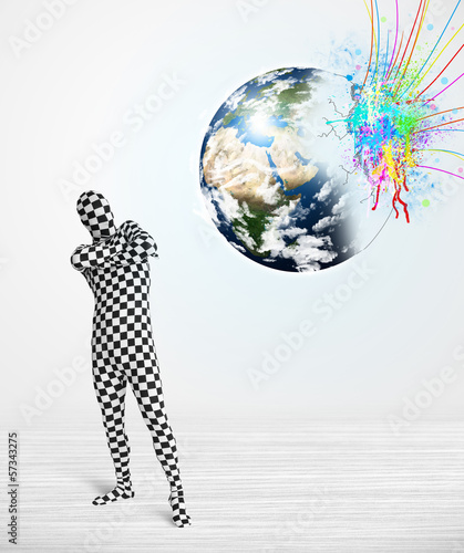 Photo: Funny man in body suit looking at colorful splatter earth Funny man in body suit looking at colorful splatter earth