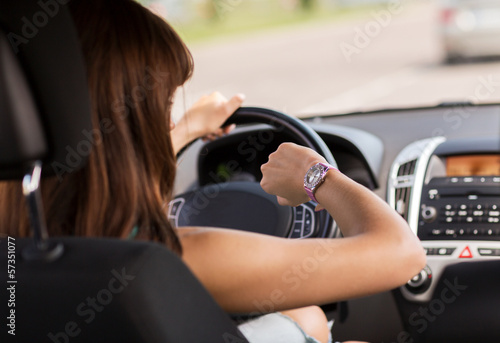 Photo: woman driving a car and looking at watch woman driving a car and looking at watch