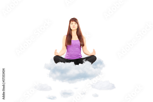 Photo: Young female athlete in outfit sitting on clouds and meditating Young female athlete in outfit sitting on clouds and meditating