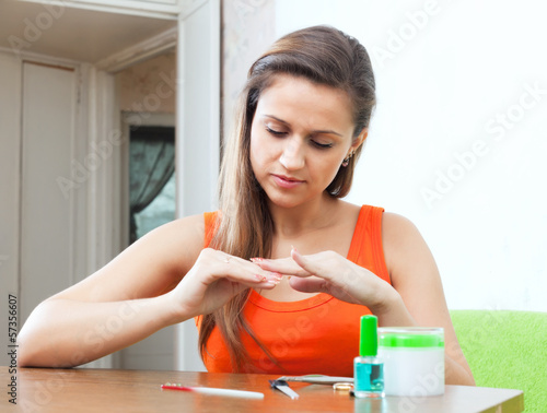 Photo: Serious woman looks at nails Serious woman looks at nails
