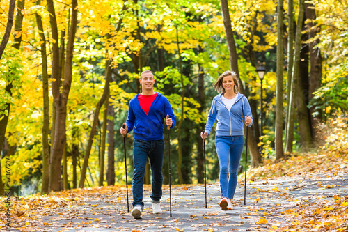 Photo: Nordic walking - active people working out outdoor Nordic walking - active people working out outdoor