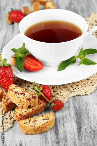 Photo: Cup of tea with cookies and strawberries on table close-up Cup of tea with cookies and strawberries on table close-up