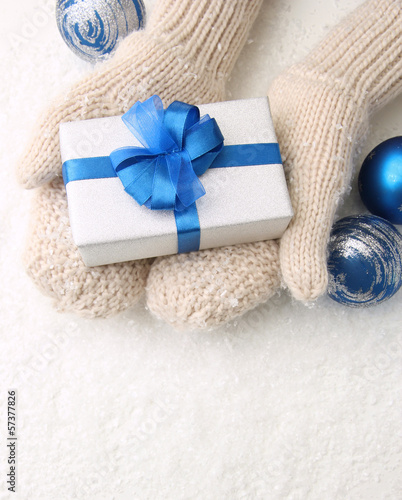 Photo: Female hands in mittens with gift box, on white background Female hands in mittens with gift box, on white background