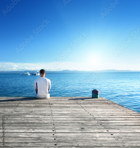 Photo: young man relax siting on pier young man relax siting on pier