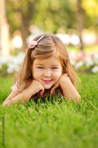 Photo: Happy beautiful little girl lying on the grass Happy beautiful little girl lying on the grass