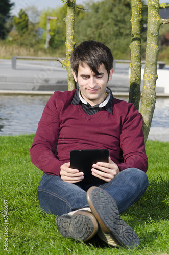 Photo: junger mann schaut auf tablet computer junger mann schaut auf tablet computer