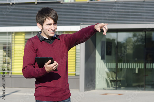Photo: junger mann mit tablet zeigt in die ferne junger mann mit tablet zeigt in die ferne