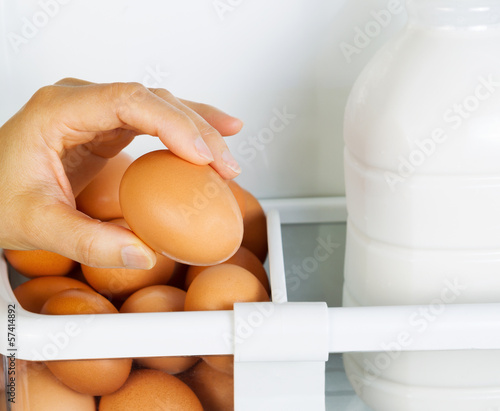 Photo: Female Hand picking one large egg from Refrigerator Female Hand picking one large egg from Refrigerator