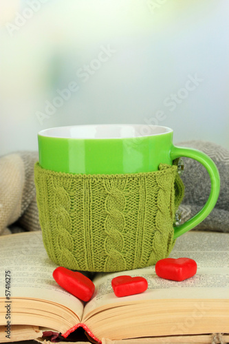 Photo: Cup with knitted thing on it and open book close up Cup with knitted thing on it and open book close up