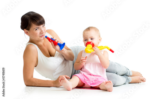 Photo: Mother and baby girl having fun with musical toys. Isolated on w Mother and baby girl having fun with musical toys. Isolated on w