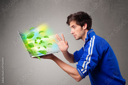Photo: Casual boy holding laptop with recycle and environmental symbols Casual boy holding laptop with recycle and environmental symbols