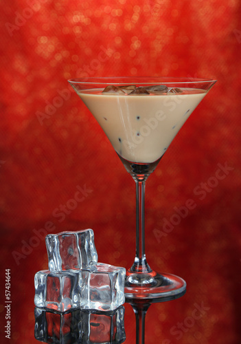 Photo: Baileys liqueur in glass on red background Baileys liqueur in glass on red background