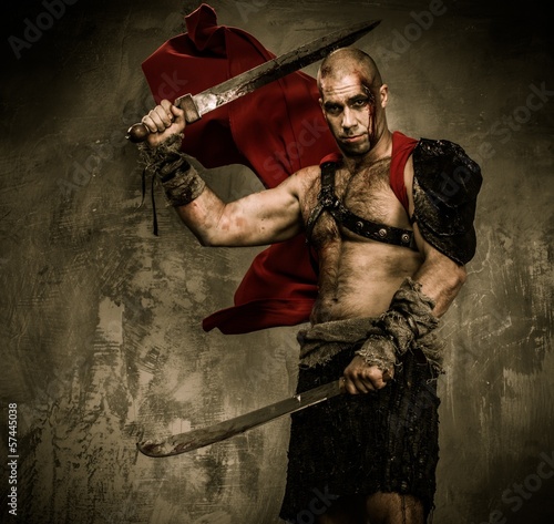 Photo: Wounded gladiator with two swords covered in blood Wounded gladiator with two swords covered in blood