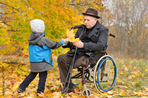 Photo: Young child giving an elderly man autumn leaves Young child giving an elderly man autumn leaves