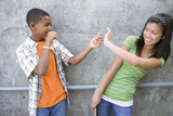 Foto: Teenage boy (13-15) preparing to flick rubber band at teenage girl (13-15), smiling Teenage boy (13-15) preparing to flick rubber band at teenage girl (13-15), smiling