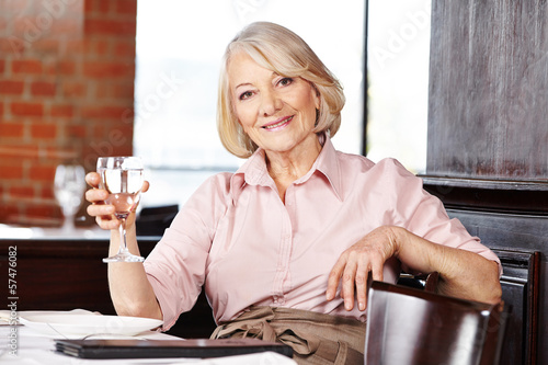 Photo: Senior woman drinking water in restaurant Senior woman drinking water in restaurant
