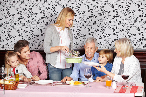 Photo: Mother serving food to family at dinner Mother serving food to family at dinner