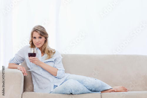 Photo: A woman looking at the camera is holding a glass of red wine A woman looking at the camera is holding a glass of red wine