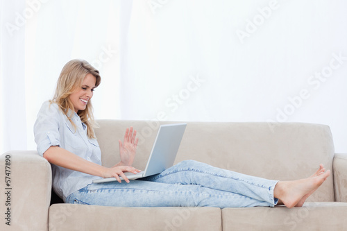 Photo: A happy woman sitting on a couch is using her laptop A happy woman sitting on a couch is using her laptop