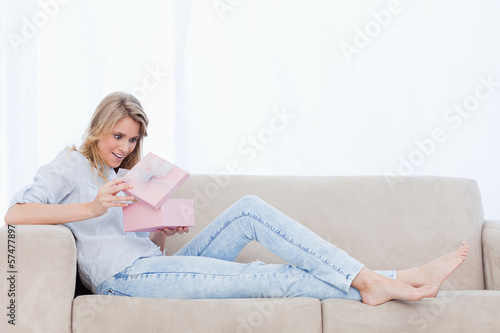 Photo: A surprised woman looks at a present inside a pink box A surprised woman looks at a present inside a pink box