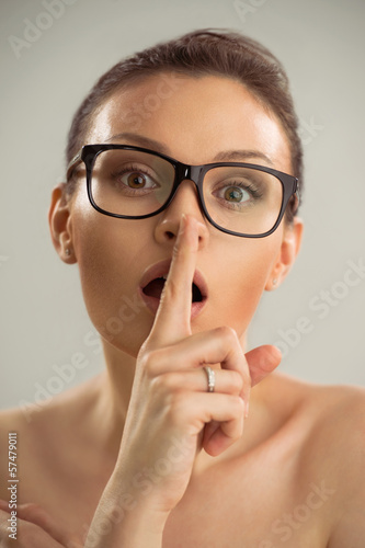 Photo: Closeup photo of woman wearing glasses and making a hush gesture Closeup photo of woman wearing glasses and making a hush gesture