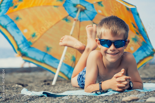 Photo: happy smiling kid is sunbathing on a beach happy smiling kid is sunbathing on a beach