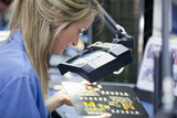Photo: Technician examining printed circuit board in hi-tech electronics manufacturing plant Technician examining printed circuit board in hi-tech electronics manufacturing plant