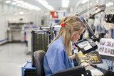 Foto: Technician examining printed circuit board in hi-tech electronics manufacturing plant Technician examining printed circuit board in hi-tech electronics manufacturing plant