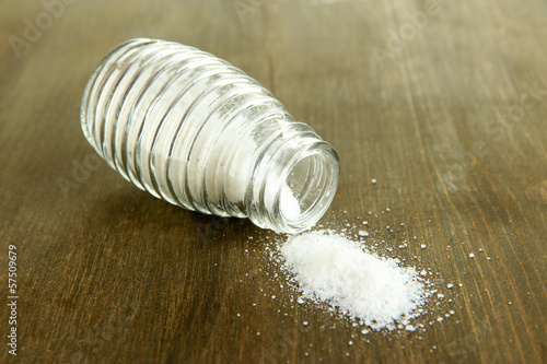 Photo: Glass saltcellar with salt on wooden background Glass saltcellar with salt on wooden background