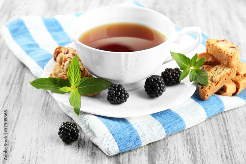 Photo: Cup of tea with cookies and blackberry on table close-up Cup of tea with cookies and blackberry on table close-up