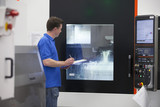 Photo: Technician with clipboard watching lathe cutting machine in hi-tech manufacturing plant Technician with clipboard watching lathe cutting machine in hi-tech manufacturing plant