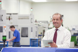 Photo: Portrait of smiling businessman with digital tablet in hi-tech manufacturing plant Portrait of smiling businessman with digital tablet in hi-tech manufacturing plant