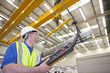 Photo: Portrait of confident businessman in front of robotic machinery lifting steel fencing on production line in manufacturing plant Portrait of confident businessman in front of robotic machinery lifting steel fencing on production line in manufacturing plant