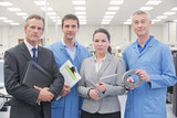 Photo: Portrait of confident business people and engineers in machine part manufacturing plant Portrait of confident business people and engineers in machine part manufacturing plant