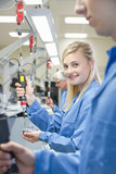 Photo : Portrait of smiling technician using electric screwdriver to assemble machine part on production line in manufacturing plant Portrait of smiling technician using electric screwdriver to assemble machine part on production line in manufacturing plant